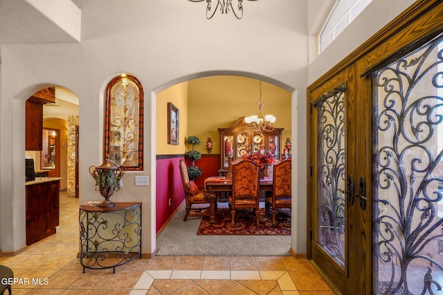 dining space with a notable chandelier, a towering ceiling, french doors, and light tile patterned flooring