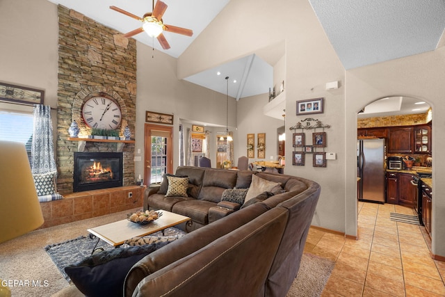 living room with a fireplace, light tile patterned floors, high vaulted ceiling, and ceiling fan