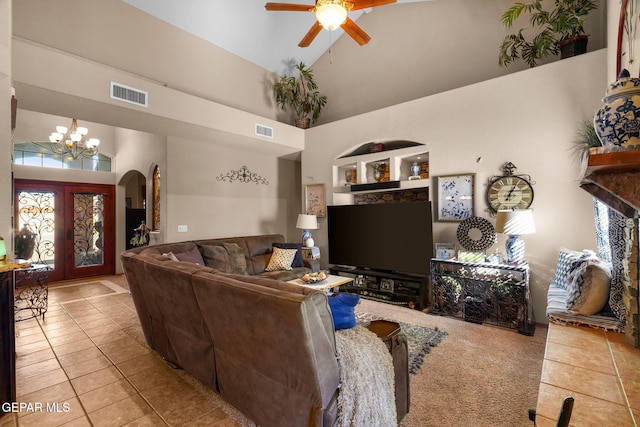 living room with ceiling fan with notable chandelier, high vaulted ceiling, french doors, and light tile patterned floors