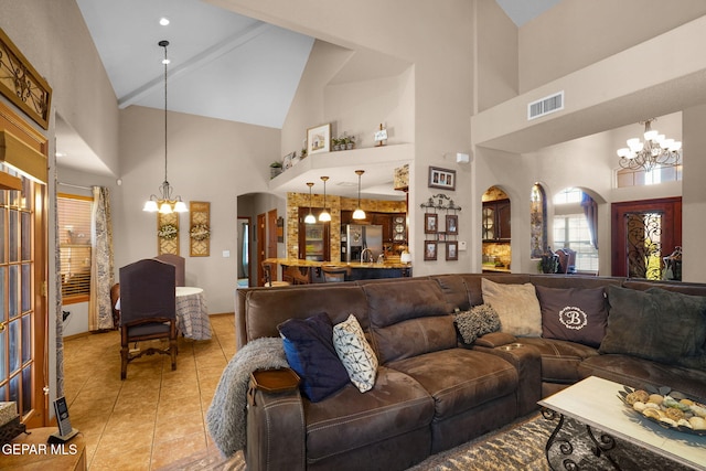 living room with a chandelier, light tile patterned floors, and high vaulted ceiling