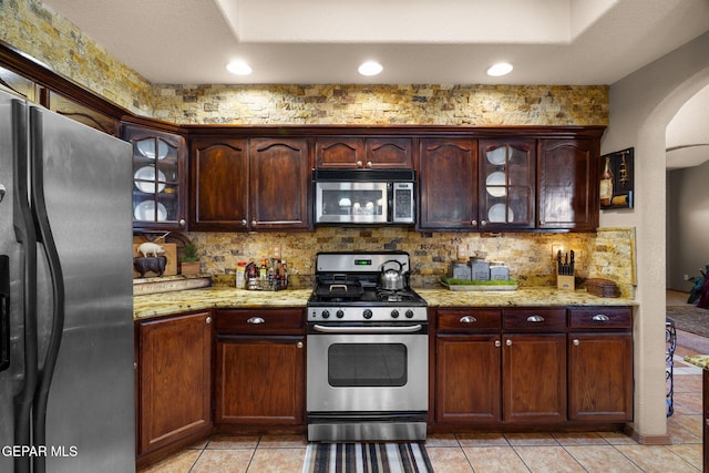 kitchen featuring light stone counters, light tile patterned floors, appliances with stainless steel finishes, and tasteful backsplash