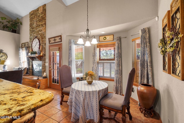 tiled dining room featuring a chandelier, a fireplace, and lofted ceiling