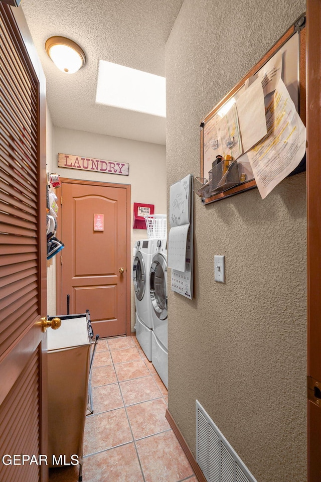 washroom featuring a textured ceiling, light tile patterned floors, and independent washer and dryer