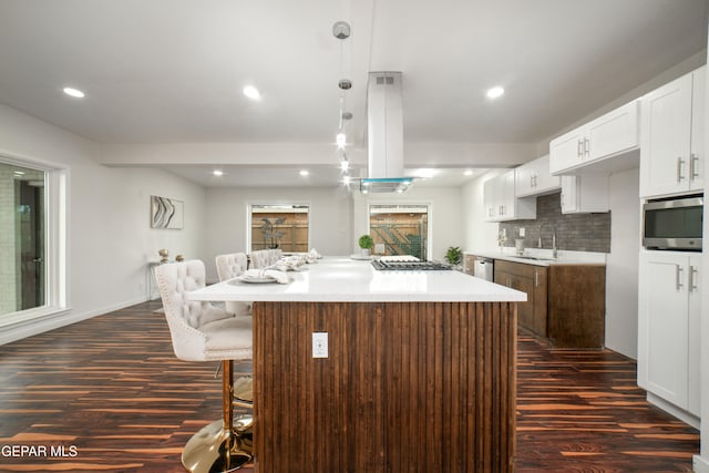 kitchen featuring white cabinetry, island range hood, a large island, and tasteful backsplash