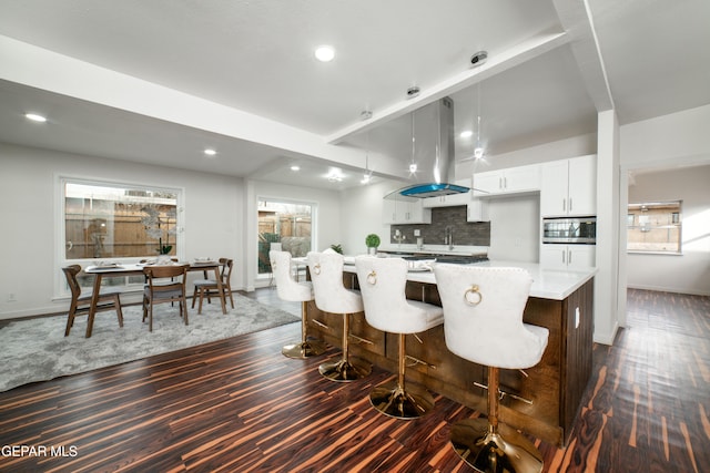 kitchen featuring pendant lighting, white cabinetry, a kitchen breakfast bar, tasteful backsplash, and a kitchen island