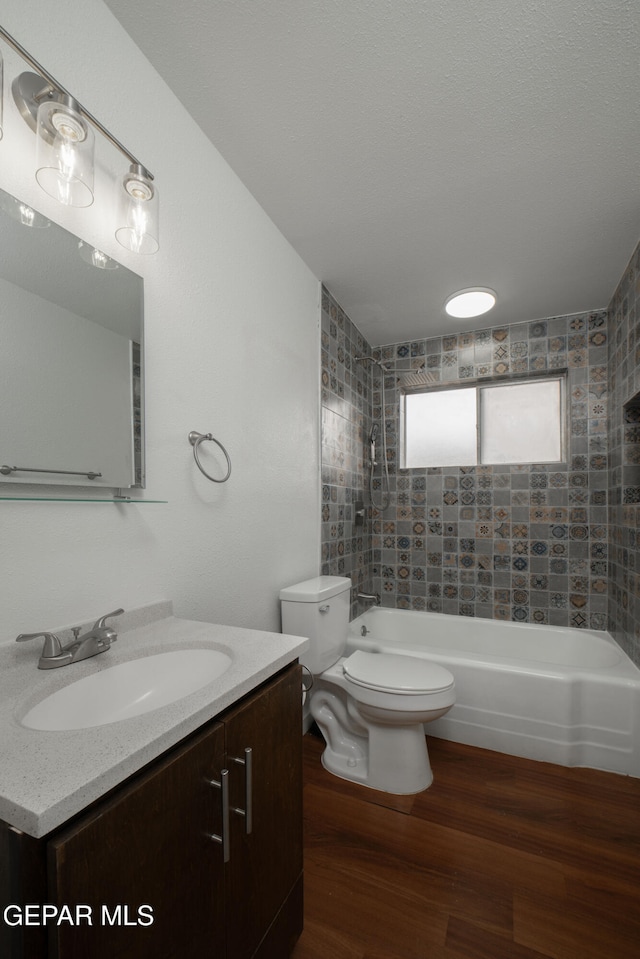 full bathroom featuring tiled shower / bath, hardwood / wood-style floors, vanity, and toilet