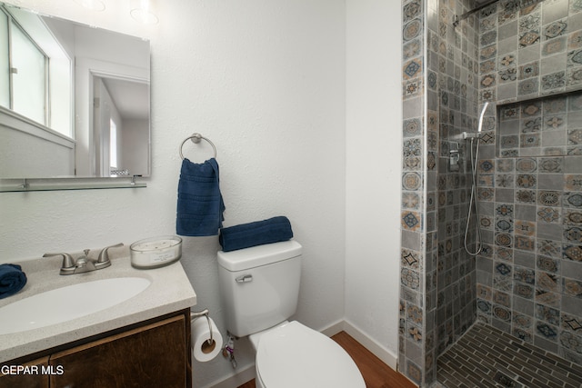 bathroom with vanity, toilet, and a tile shower