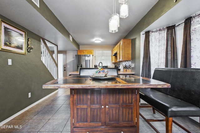 kitchen featuring tasteful backsplash, a wealth of natural light, pendant lighting, and stainless steel refrigerator with ice dispenser