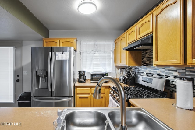 kitchen with backsplash, sink, and appliances with stainless steel finishes