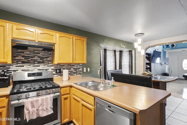 kitchen with decorative backsplash, kitchen peninsula, sink, and appliances with stainless steel finishes