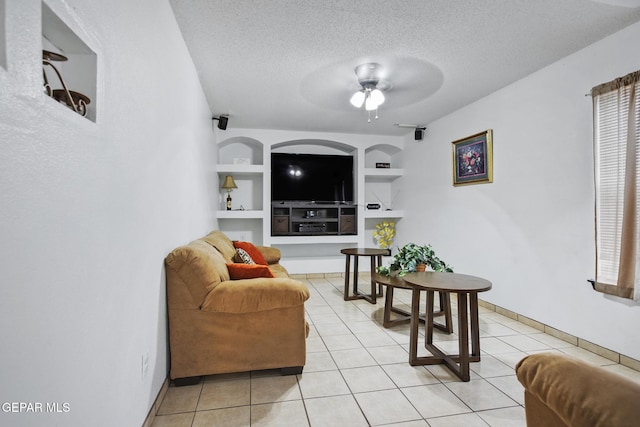 tiled living room with ceiling fan, built in features, and a textured ceiling