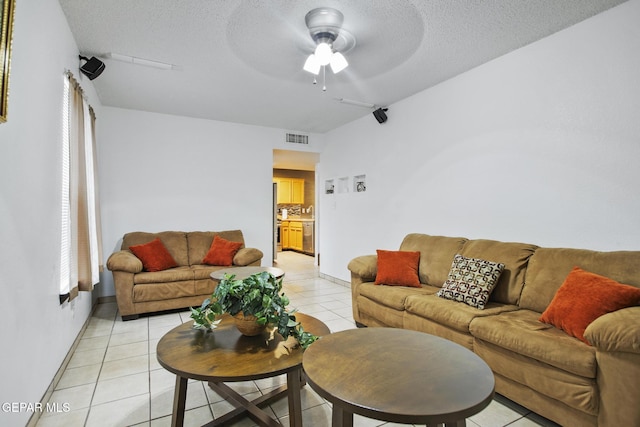 living room featuring ceiling fan, light tile patterned flooring, and a textured ceiling