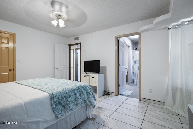 bedroom with a textured ceiling, ensuite bath, and ceiling fan