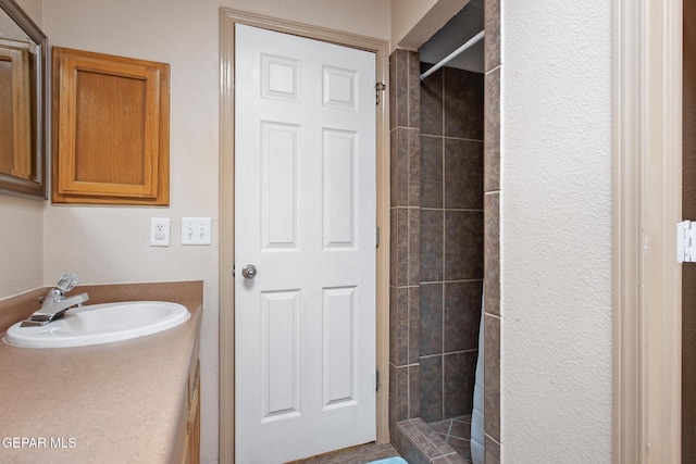 bathroom with a tile shower and sink