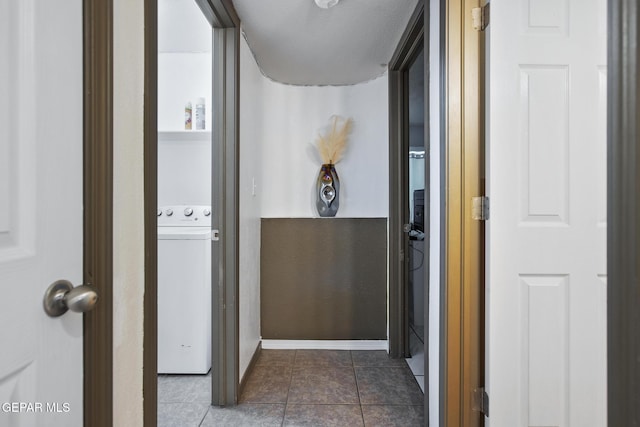 corridor featuring tile patterned floors, a textured ceiling, and washer / dryer