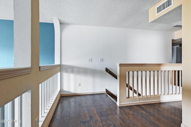 corridor with hardwood / wood-style floors and a textured ceiling