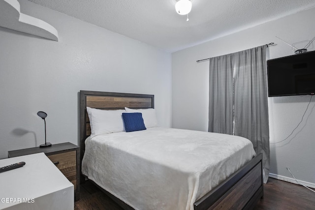 bedroom with a textured ceiling and dark hardwood / wood-style flooring