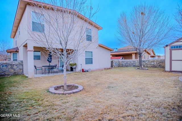 rear view of property with a storage shed, a yard, and a patio