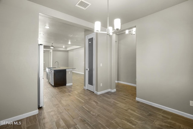 interior space featuring decorative light fixtures, sink, a kitchen island with sink, and an inviting chandelier