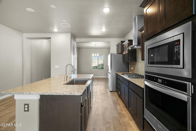 kitchen featuring dark brown cabinets, an island with sink, appliances with stainless steel finishes, and a chandelier