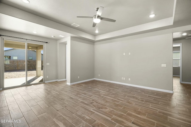 unfurnished room with ceiling fan, plenty of natural light, and a tray ceiling