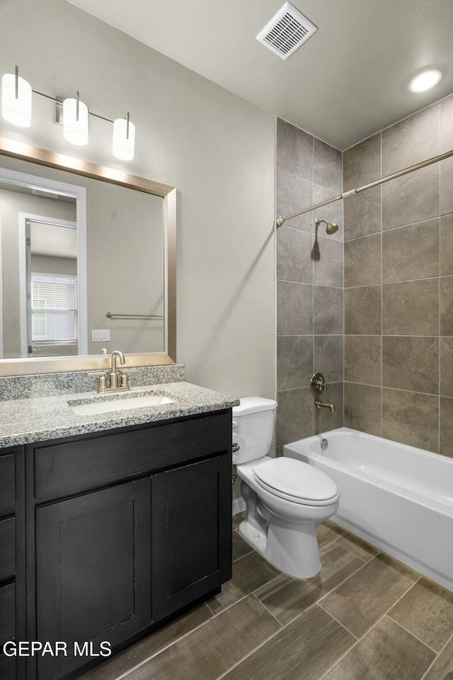 full bathroom with tiled shower / bath combo, toilet, and vanity