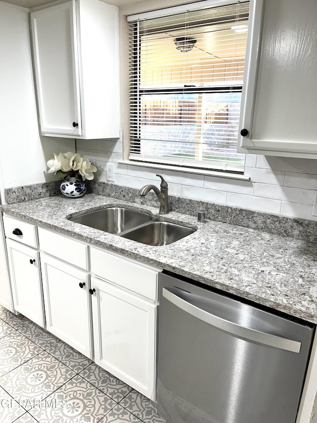 kitchen featuring backsplash, white cabinetry, sink, and stainless steel dishwasher