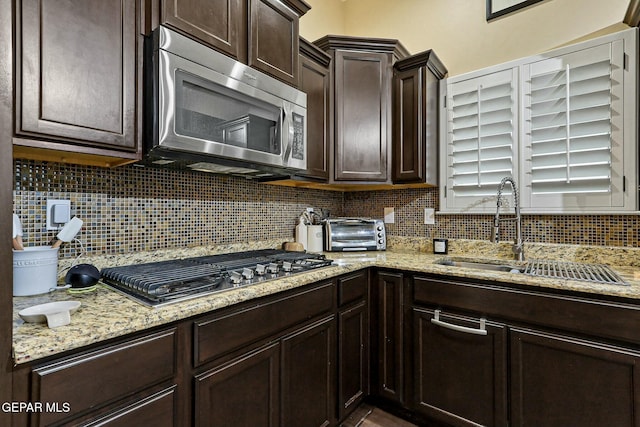 kitchen featuring backsplash, sink, stainless steel appliances, and dark brown cabinets