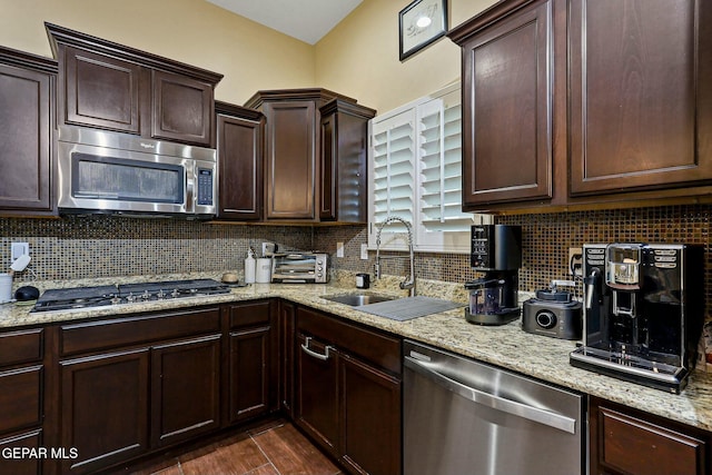 kitchen with decorative backsplash, appliances with stainless steel finishes, light stone countertops, and sink