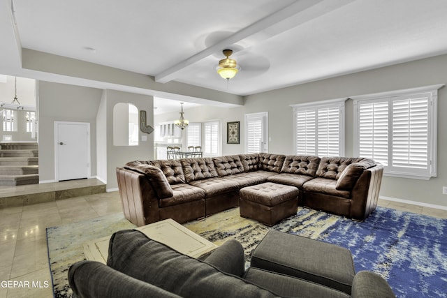 tiled living room featuring beamed ceiling and ceiling fan with notable chandelier