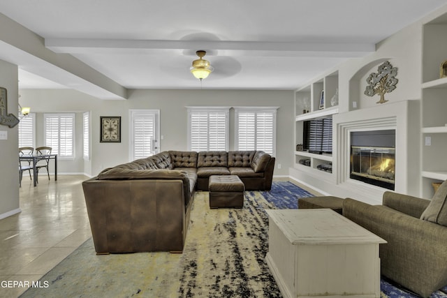 living room with beamed ceiling, plenty of natural light, built in features, and ceiling fan with notable chandelier