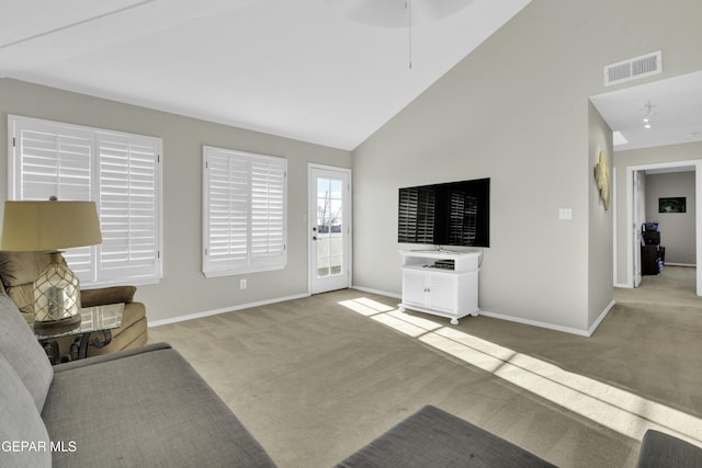 carpeted living room with high vaulted ceiling