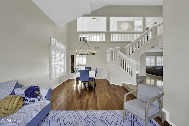 living room featuring a high ceiling, an inviting chandelier, and wood-type flooring