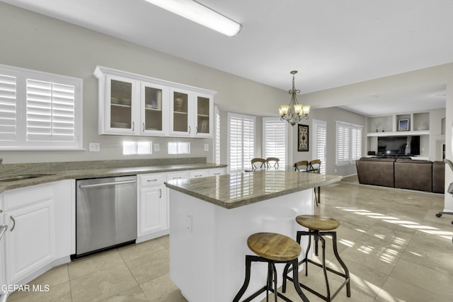 kitchen with an inviting chandelier, white cabinets, stainless steel dishwasher, decorative light fixtures, and a breakfast bar area