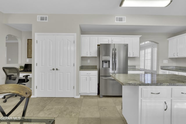 kitchen featuring dark stone countertops, white cabinetry, light tile patterned flooring, and stainless steel refrigerator with ice dispenser