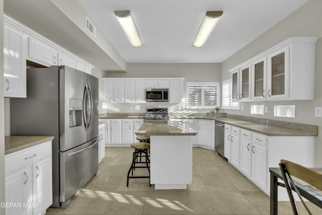 kitchen featuring white cabinets, a kitchen bar, stainless steel appliances, and a kitchen island