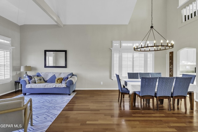 dining area with a towering ceiling, dark hardwood / wood-style flooring, and an inviting chandelier