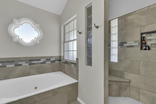 bathroom featuring a wealth of natural light, tiled tub, and vaulted ceiling