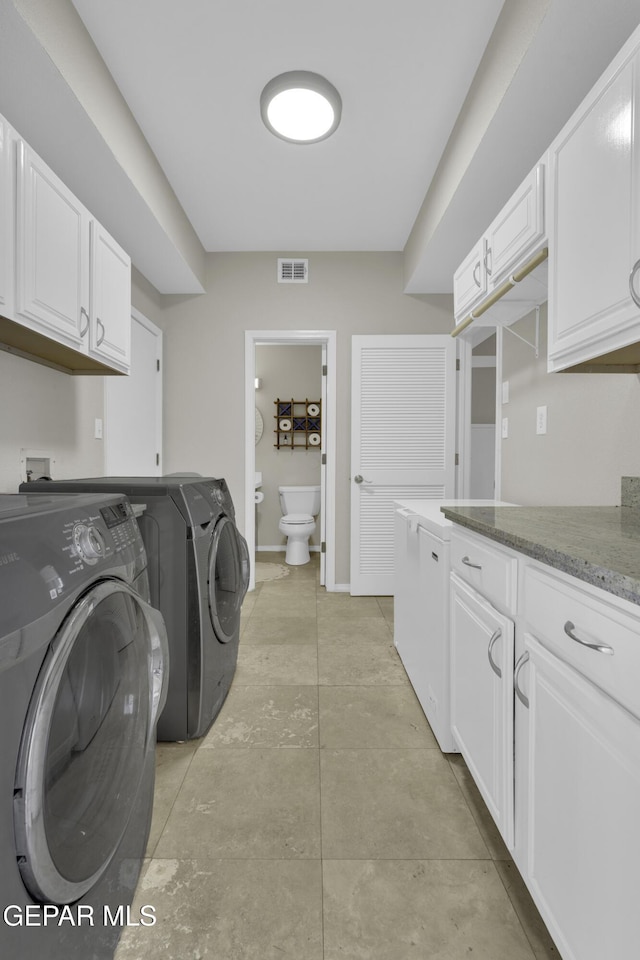 clothes washing area with cabinets and independent washer and dryer