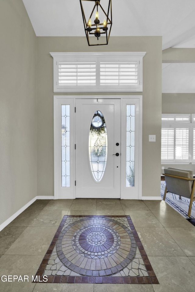 tiled foyer entrance with a chandelier