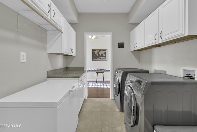 clothes washing area featuring cabinets, washer and dryer, and light tile patterned flooring