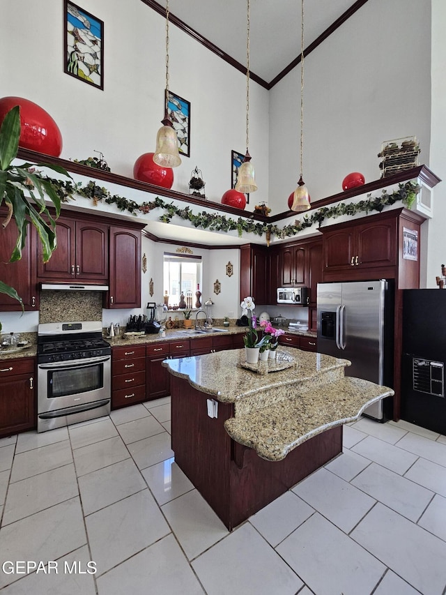 kitchen with pendant lighting, a center island, stainless steel appliances, and a high ceiling