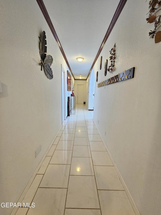 corridor with light tile patterned floors and ornamental molding