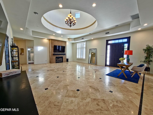 living room featuring a raised ceiling, a fireplace, and an inviting chandelier