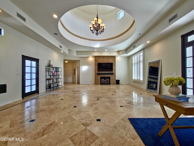 living room with a raised ceiling, a towering ceiling, a fireplace, and an inviting chandelier