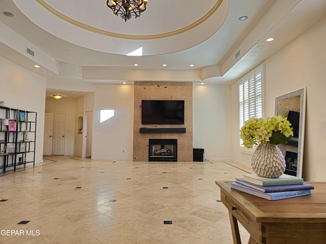 living room with a raised ceiling, a fireplace, and an inviting chandelier