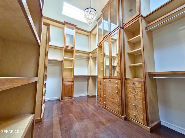 spacious closet with dark hardwood / wood-style floors and an inviting chandelier