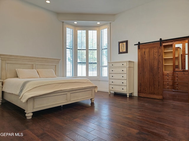 bedroom featuring a barn door and dark wood-type flooring