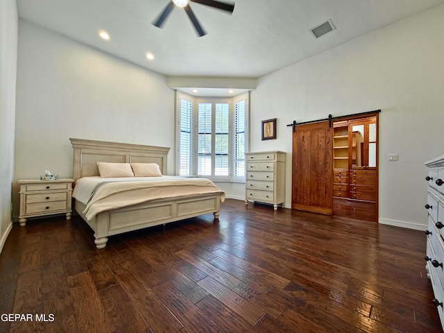 bedroom with dark hardwood / wood-style flooring, a barn door, and ceiling fan