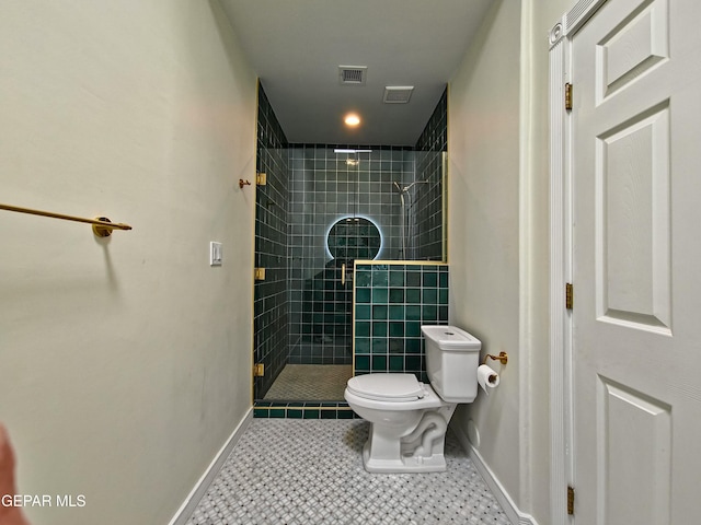 bathroom featuring tile patterned floors, toilet, and a tile shower